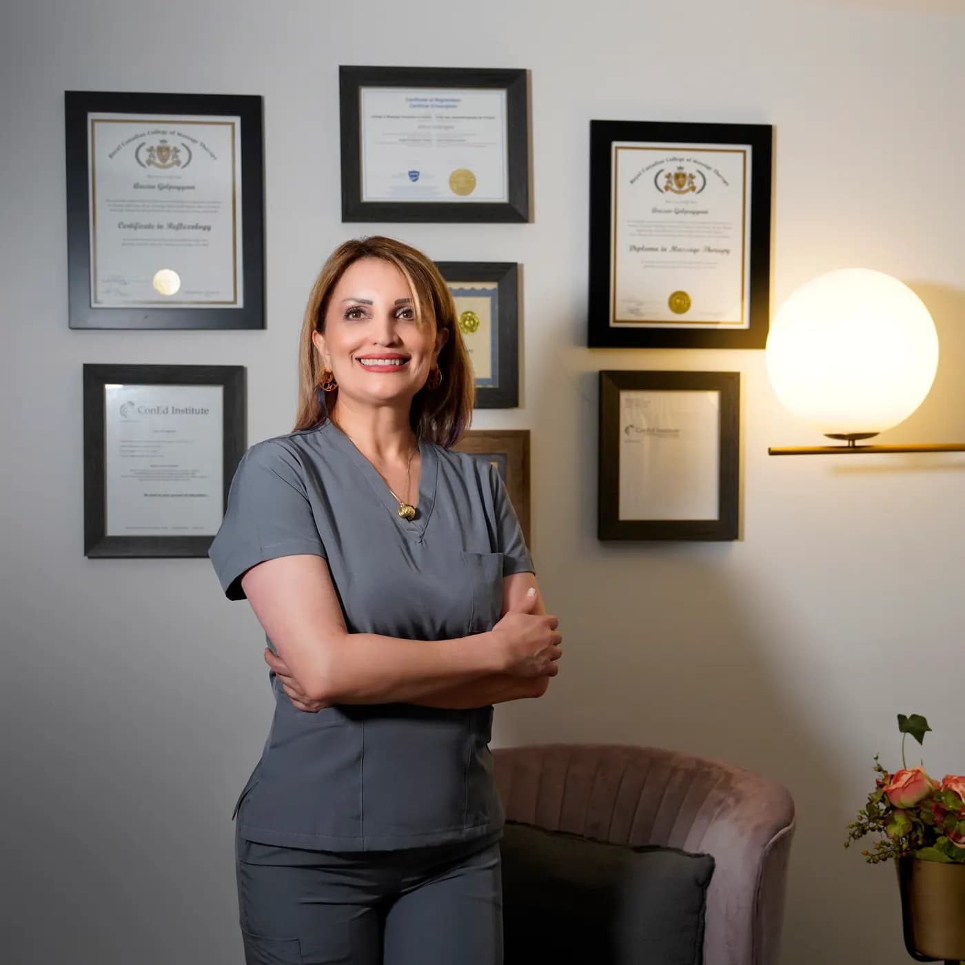 Therapist standing before a wall of framed professional certifications