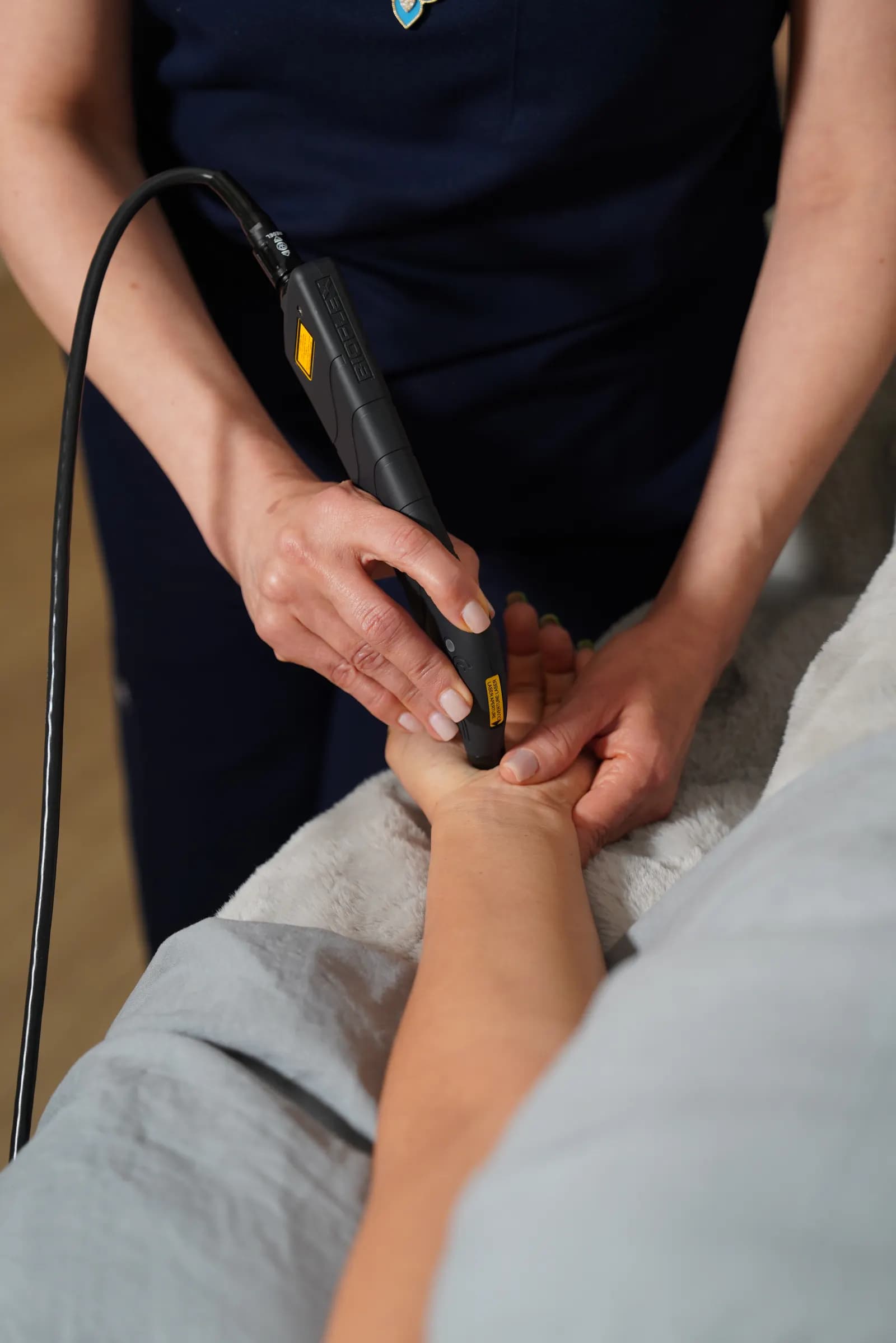 Handheld laser therapy probe treating a client's foot
